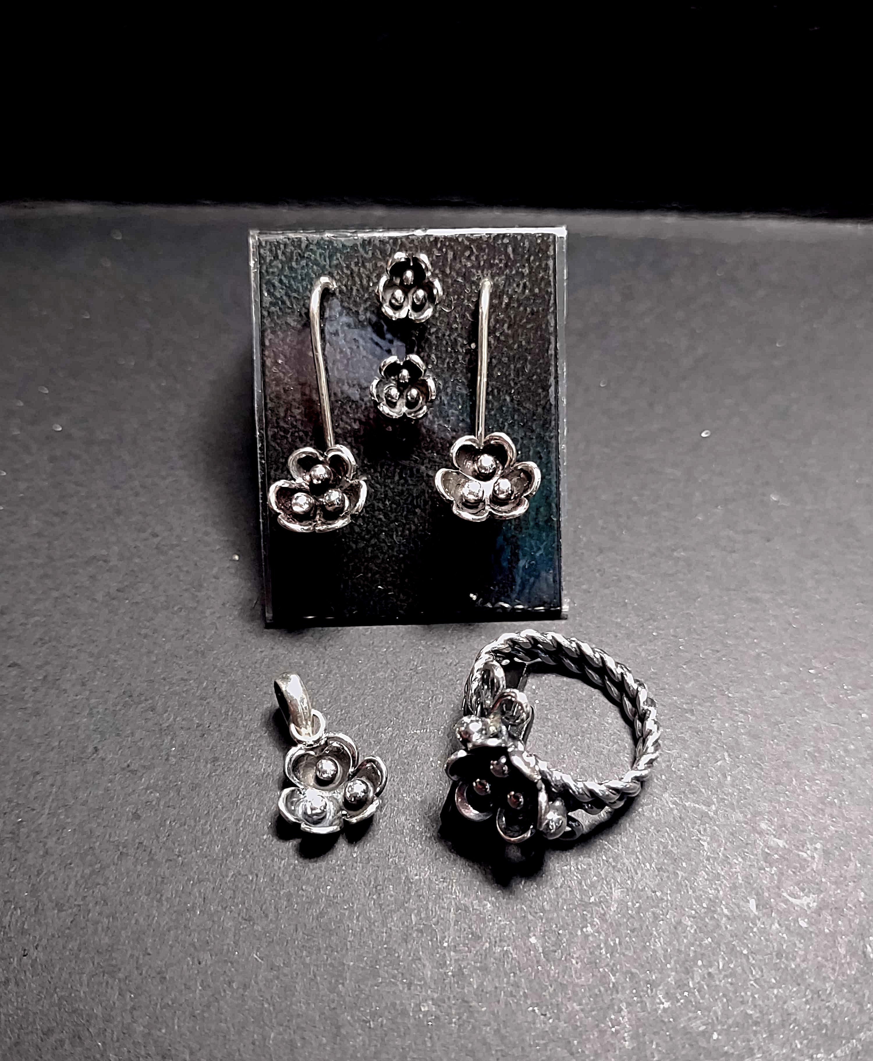 a silver pair of stud earrings, long stiff earrings, pendant and ring with an allium flower on each