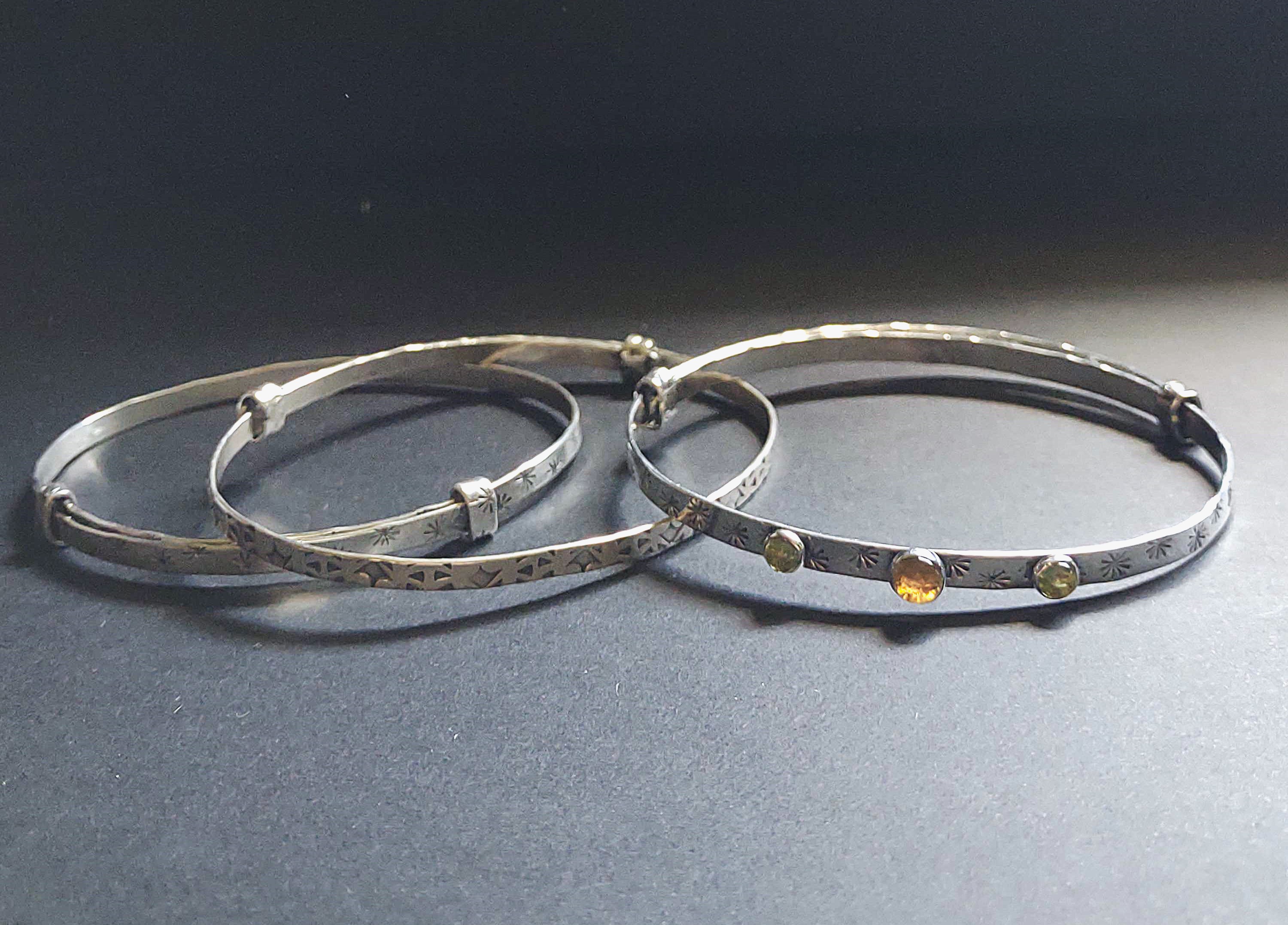 three silver bracelets, one with stones and two without